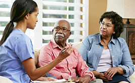 Nurse Making Notes During Home Visit With Senior Couple